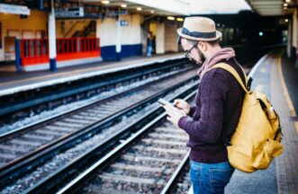 Man wacht op de trein en kijkt naar z'n smartphone