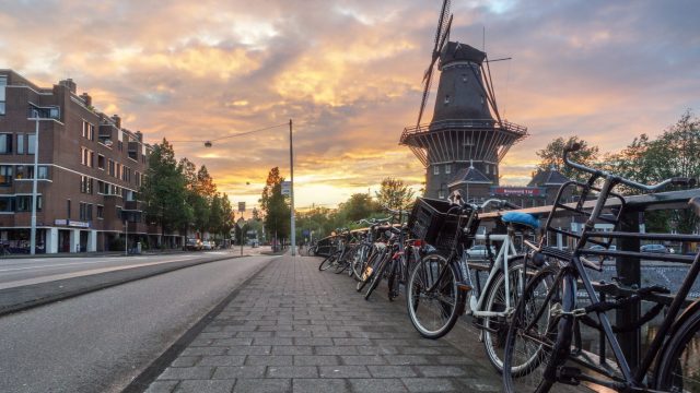 Een lege straat met fietsen en een molen.